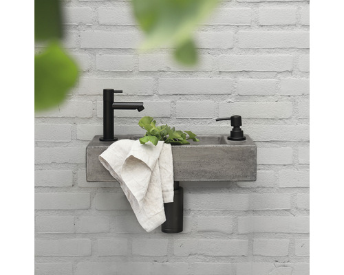 Waschbecken mit Armatur und Seifenspender an einer Wand