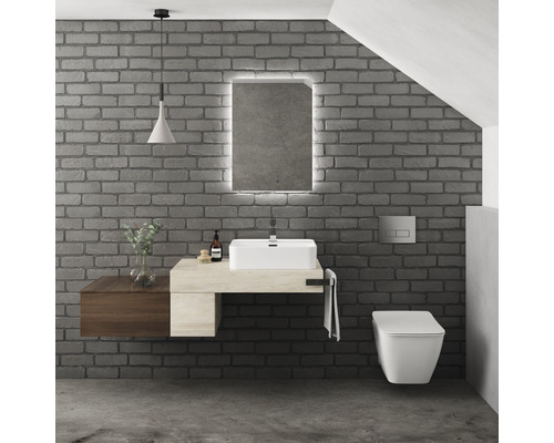 Salle de bains moderne avec lavabo, miroir avec éclairage et toilettes suspendues devant un mur de briques