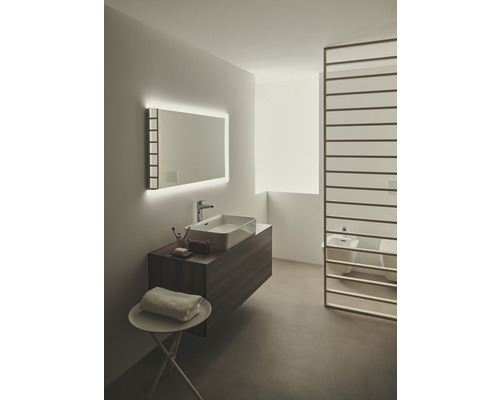 Salle de bains lumineuse avec lavabo, miroir avec éclairage et séparation de pièce