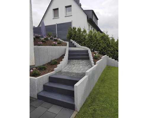 Treppenanlage mit Stufen und Mauern im Gartenbereich vor einem Wohnhaus.