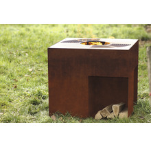 Quadratische Feuersäule aus Stahl mit Holzscheiten auf einer Rasenfläche.