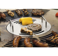 Verschiedene Lebensmittel werden auf einem Grill zubereitet, darunter Würstchen, Fleisch und Gemüse.