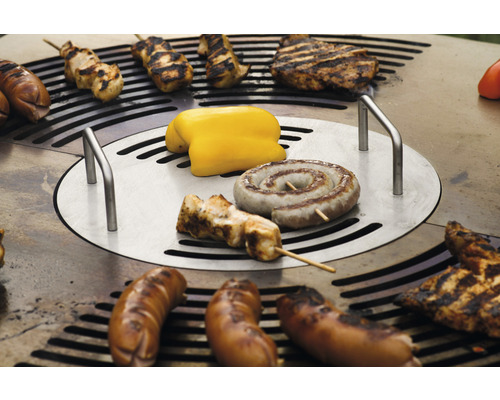 Verschiedene Lebensmittel werden auf einem Grill zubereitet, darunter Würstchen, Fleisch und Gemüse.