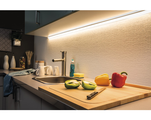 Scène de cuisine avec évier, robinet, planche à découper et luminaire LED sous l''armoire suspendue