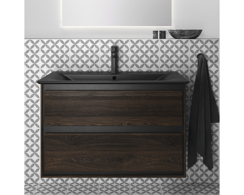 Meuble sous-vasque avec aspect bois foncé et lavabo noir ainsi que robinetterie devant un mur à motifs