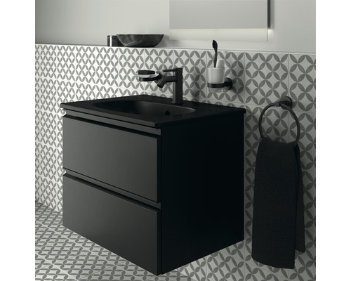 Meuble-lavabo noir avec deux tiroirs, robinetterie, distributeur de savon, gobelet à brosse à dents et porte-serviettes devant un mur à motifs