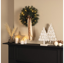 Arrangement décoratif avec couronne, bougies LED et sapins décoratifs sur un manteau de cheminée