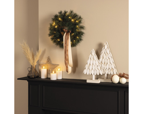 Arrangement décoratif avec couronne, bougies LED et sapins décoratifs sur un manteau de cheminée