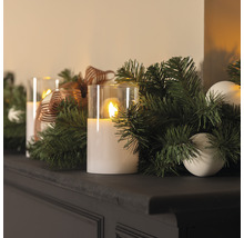 Arrangement décoratif avec bougies LED, verdure de sapin et ornements sur une étagère.