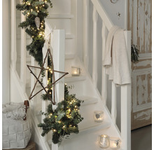 Escalier décoré avec une guirlande de sapin, des lumières, une étoile en bois et des photophores pour la période de Noël