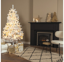 Weihnachtsbaum aus Kunstschnee mit Kugeln und Geschenken in einem Wohnzimmer mit Kamin