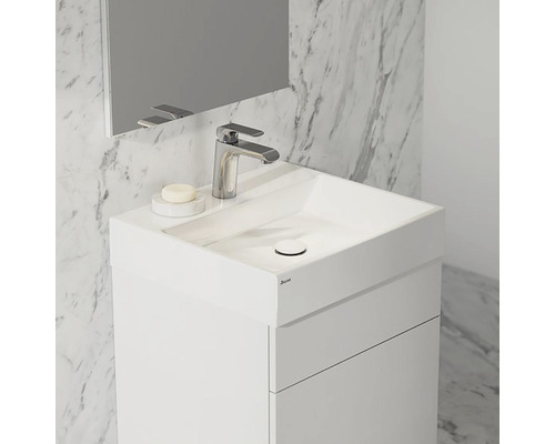 Weißer Waschtisch mit Waschbecken, Armatur und Spiegel vor Marmorwand