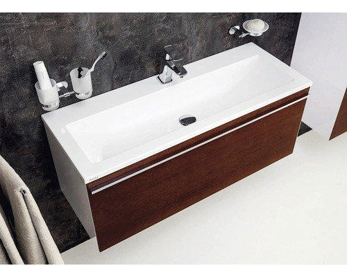 Waschtisch mit Unterschrank, Armatur, Seifenschale und Zahnputzbechergarnitur im Badezimmer.