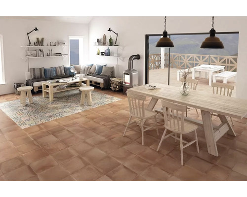 Wohnzimmer mit Holztisch, Stühlen, Sofa, Teppich und Kaminofen auf Terrakottafliesen