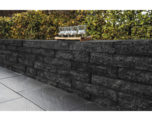 Gartenmauer aus Stein mit Pflanzen und Windlichtern