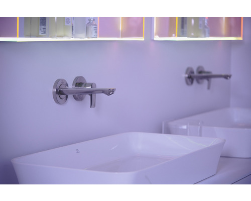 Robinet mural en acier inoxydable au-dessus d''un lavabo à poser blanc