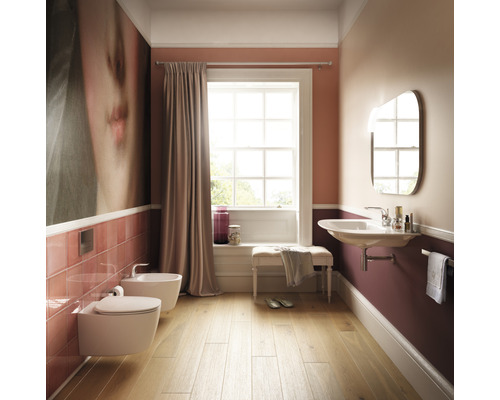 Badezimmer mit Toilette, Bidet, Waschbecken, Spiegel und Fenster für eine helle Atmosphäre.