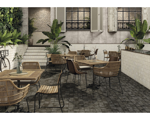 Terrasse de restaurant avec tables, chaises, plantes et sol carrelé.