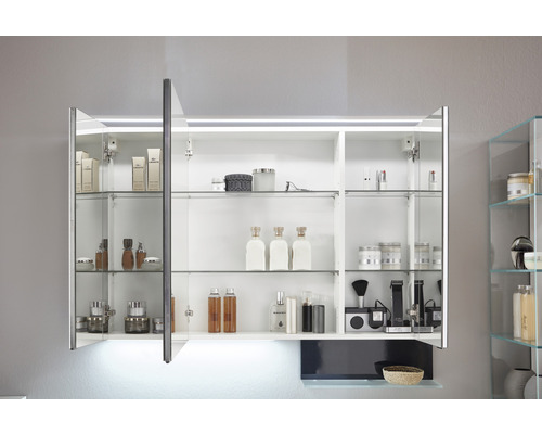 Geöffneter Spiegelschrank mit Glasböden und Beleuchtung im Badezimmer zur Aufbewahrung von Kosmetikartikeln