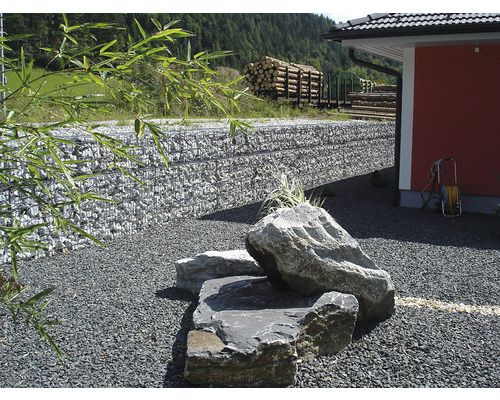 Aménagement d''un jardin avec des pierres, un mur de gabions et un stockage de bois