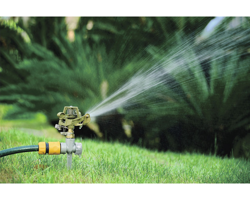 Rasensprenger bewässert Rasenfläche im Garten.