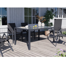 Gartenszene mit Esstisch und Stühlen auf einer Holzterrasse vor einem Haus.