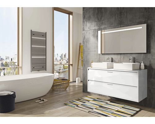 Salle de bain lumineuse avec baignoire, sèche-serviettes, meuble-lavabo avec deux lavabos et miroir éclairé.