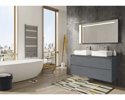 Badezimmer mit Badewanne, Handtuchwärmer, Waschtisch mit zwei Waschbecken und beleuchtetem Spiegel.