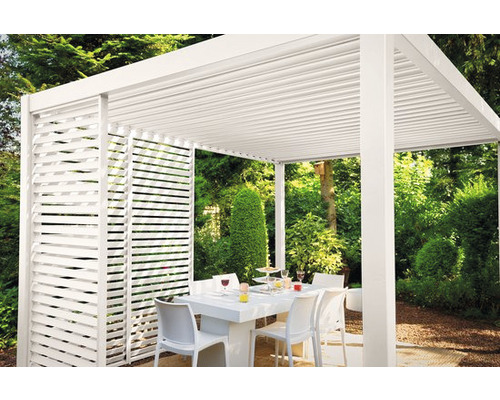 Pergola blanche avec paroi à lamelles et table à manger dans le jardin.