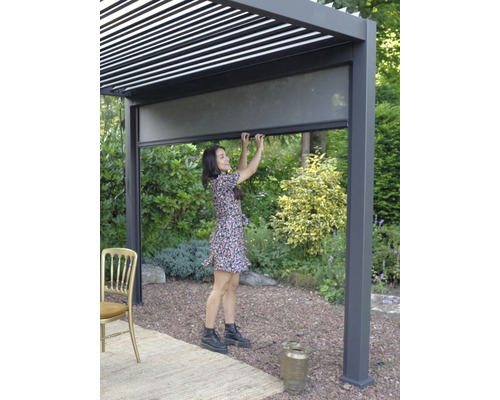 Femme manipulant une pergola avec des écrans d’intimité dans le jardin.