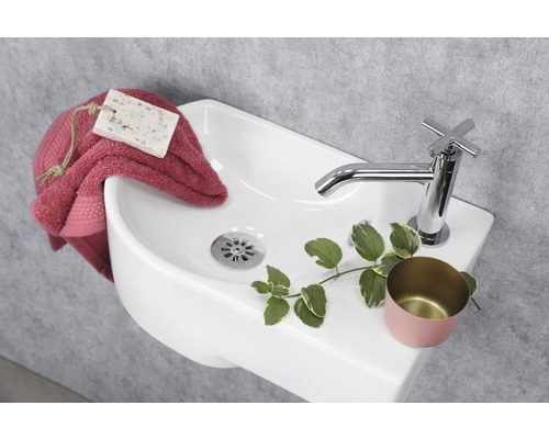 Aufsicht auf ein Keramikwaschbecken mit Armatur, Handtuch und Seife.