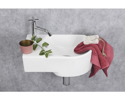 Keramikwaschbecken mit Armatur, Handtuch und Seife im Badezimmer