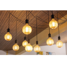 Plusieurs lampes suspendues avec des ampoules et une suspension noire sur un plafond en bois