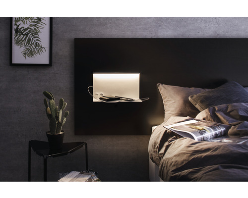 Schlafzimmer mit Bett, Nachttischlampe, Nachttisch und Zimmerpflanze