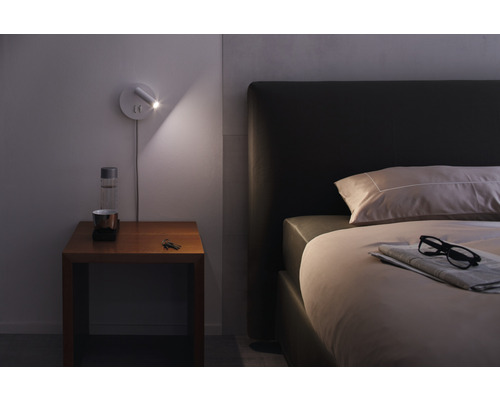 Schlafzimmer mit Bett, Nachttisch und Wandleuchte