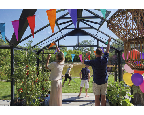 Gewächshaus mit Familie und festlicher Dekoration. Im Inneren wachsen Tomatenpflanzen.