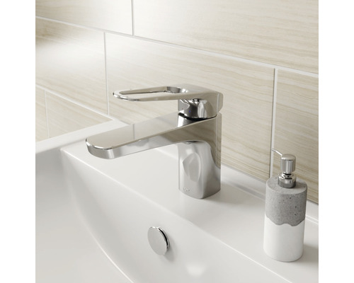 Mitigeur de lavabo brillant sur un lavabo avec distributeur de savon.