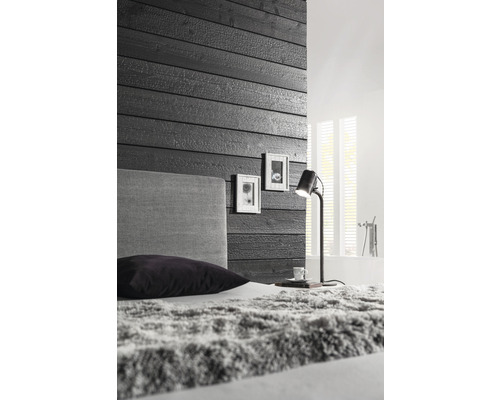 Schlafzimmer mit Holzwand, Bett und Lampe