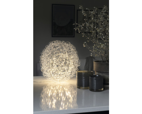 Dekorative Kugel-Tischleuchte mit Drahtgeflecht und LED-Lichtern auf einem Tisch