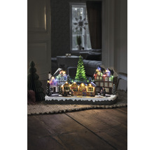 Dekorative Weihnachtsszene mit beleuchteten Häusern und Tannenbäumen auf einem Tisch