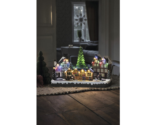 Dekorative Weihnachtsszene mit beleuchteten Häusern und Tannenbäumen auf einem Tisch