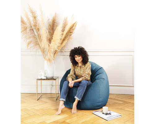 Femme assise dans un pouf bleu dans un salon lumineux