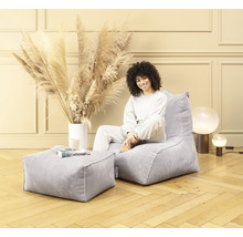 Femme assise dans un pouf en velours côtelé avec tabouret assorti dans une pièce lumineuse