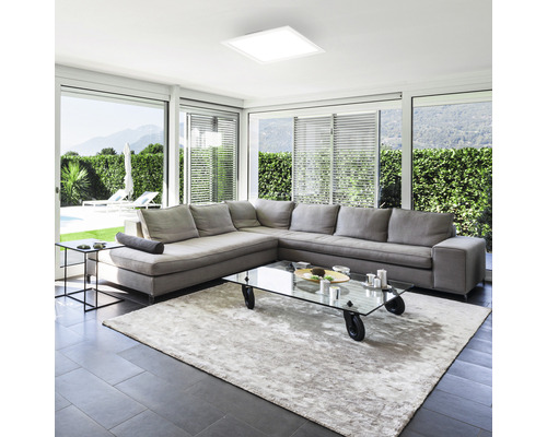 Helles Wohnzimmer mit grossem Sofa, Teppich und quadratischer Deckenleuchte