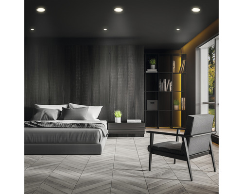 Schlafzimmer mit Bett, Sessel und Bücherregal in dunklem Design