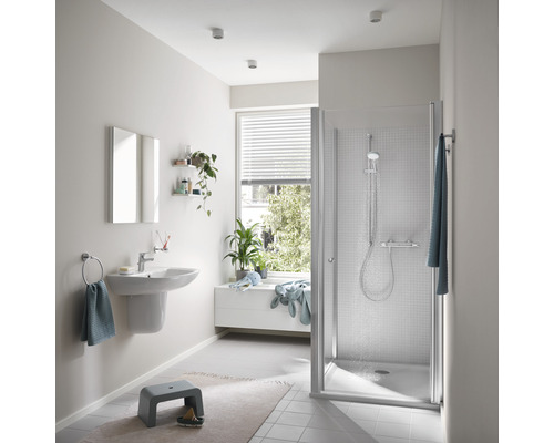 Salle de bain lumineuse avec douche, lavabo et fenêtre