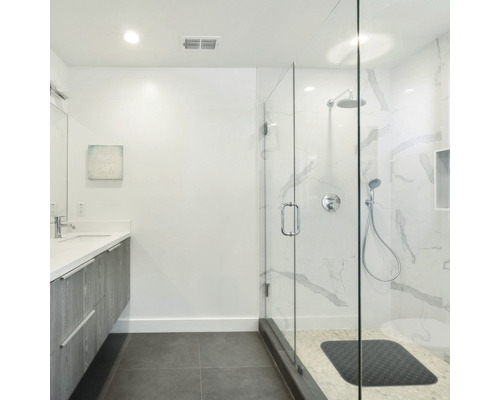 Salle de bain lumineuse avec lavabo, miroir et douche en verre