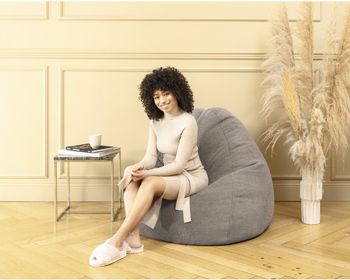 Femme assise sur un pouf gris dans un salon.
