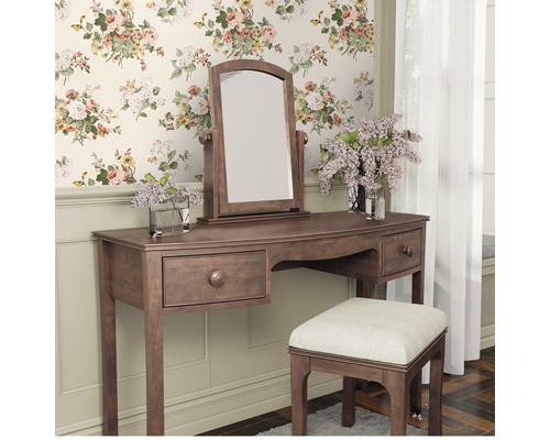 Schminktisch mit Spiegel und Hocker vor einer floralen Tapete