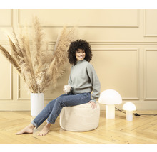 Femme assise sur un pouf dans un salon avec décoration et lampes champignons